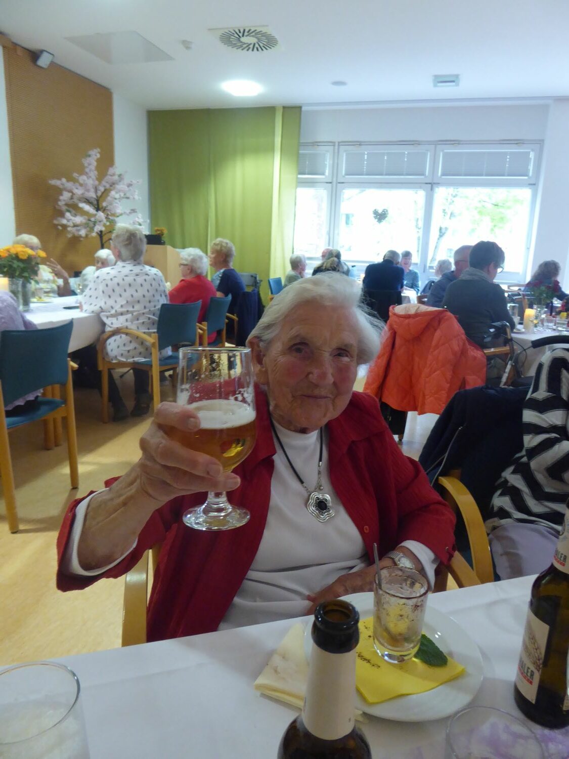 Bewohnerin des Pflegeheims mit einem Glas Bier